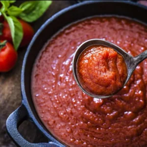 Pomodoro sauce with tomatoes and basil off to the side of saucepan and ladel